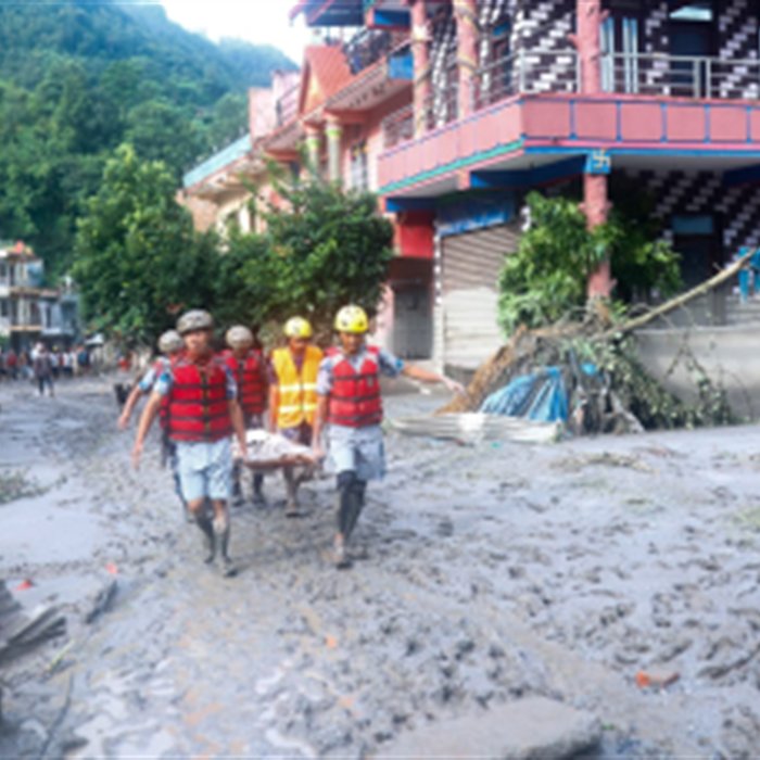 Relief workers moving through a flood-affected street in Rasuwa